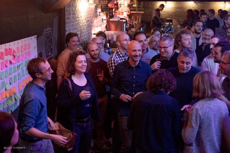 Groupe de professionnels échangeant lors d'une soirée networking dans un bar, ambiance chaleureuse