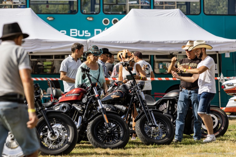 Visiteurs admirant des motos Harley-Davidson exposées sur l'herbe au festival Goulaine Country Show