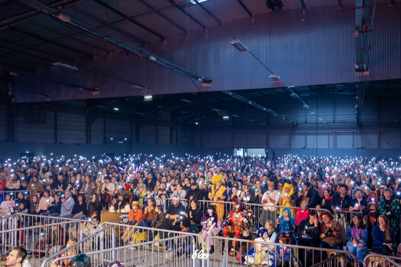 Foule immense éclairée par les lumières de téléphones dans le noir lors du concours cosplay au salon Art To Play à Nantes