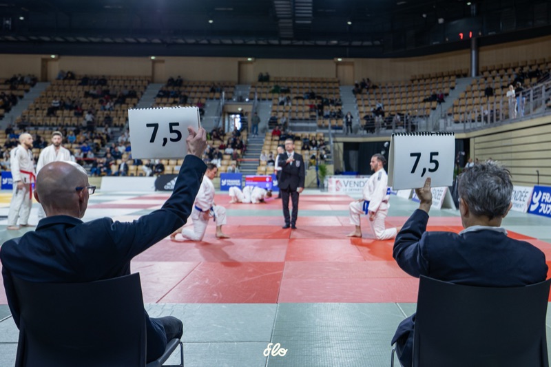 Juges levant les notes de dos face au tatami lors du Championnat de France de jujitsu au Vendespace
