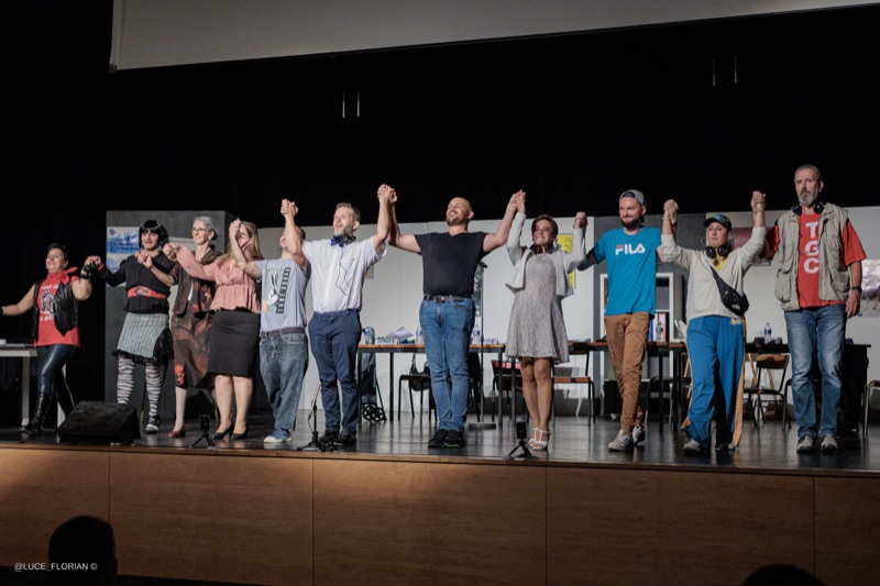 Salut final de la troupe main dans la main sur scène de la troupe de théâtre Les Loulartistes, projecteurs en contre-jour