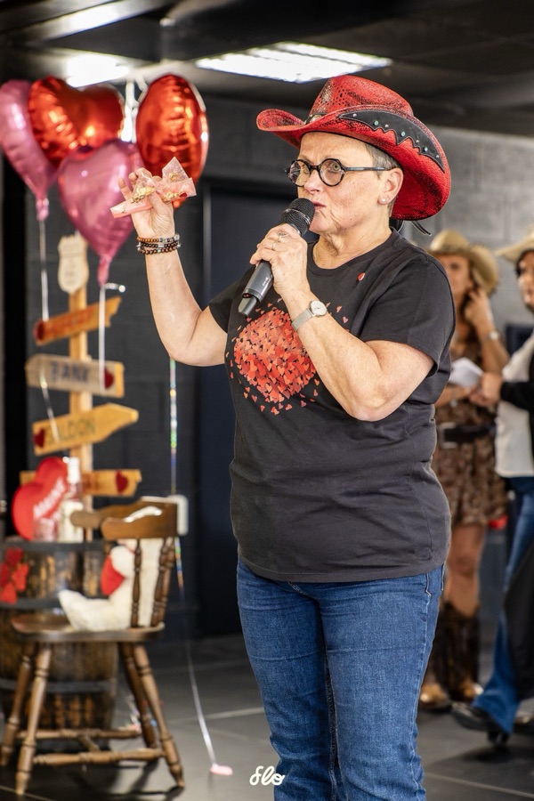 Animatrice en chapeau rouge au micro présentant les danses devant le décor de la Saint-Valentin