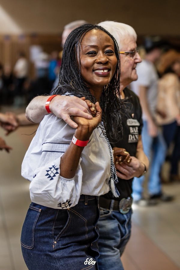 Danseuse souriante en blouse blanche exécutant un pas de danse en ligne