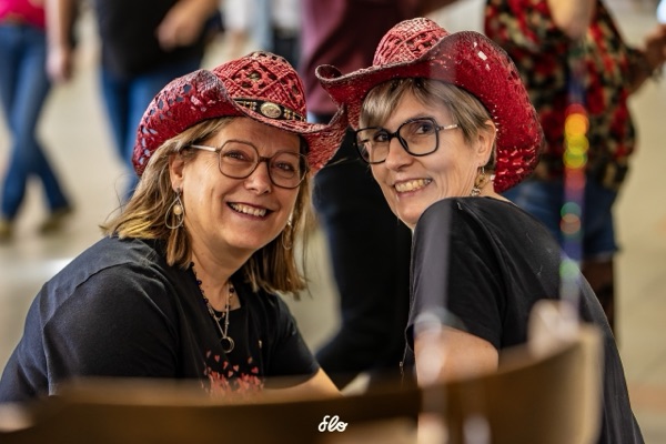Deux amies en chapeaux rouges à paillettes échangeant un sourire complice