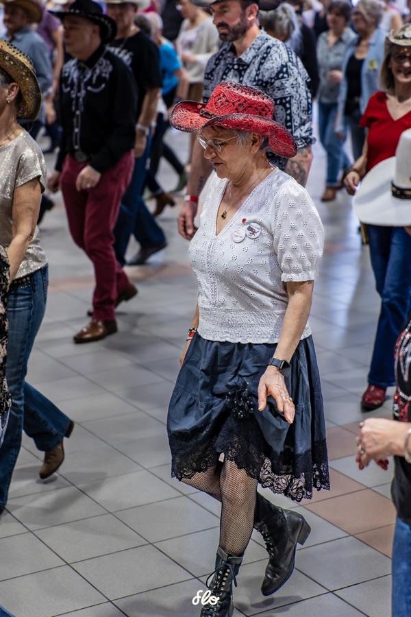 Danseuse en chapeau rouge et jupe noire exécutant un pas parmi les autres danseurs