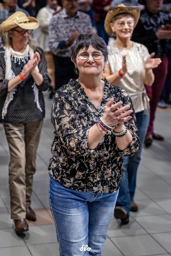 Danseuse applaudissant avec un sourire, chapeaux de cowboy en arrière-plan