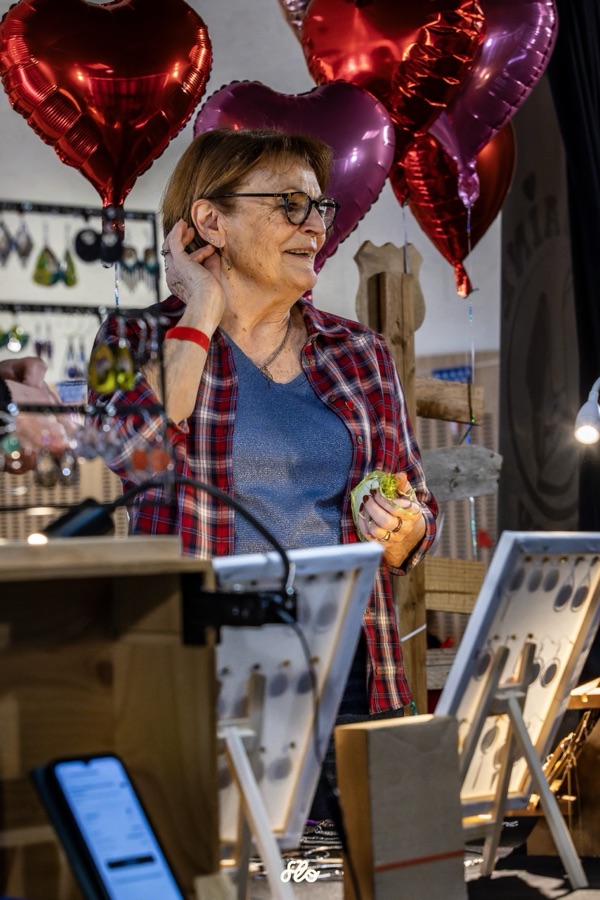 Visiteuse en chapeau de cowboy observant des bijoux sur le stand artisanal