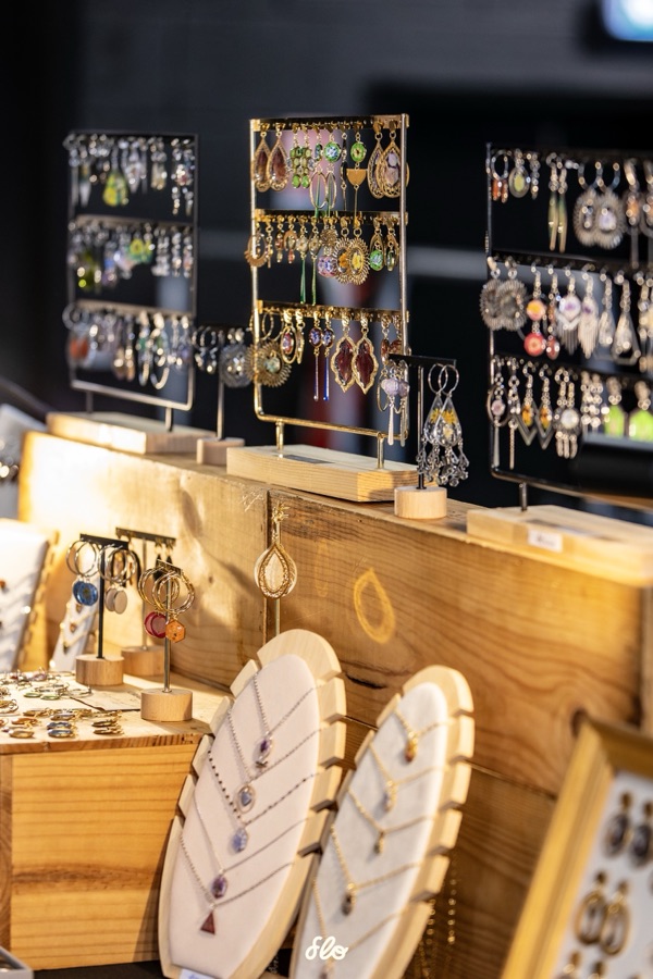 Détail des présentoirs de boucles d'oreilles et colliers artisanaux sur le stand