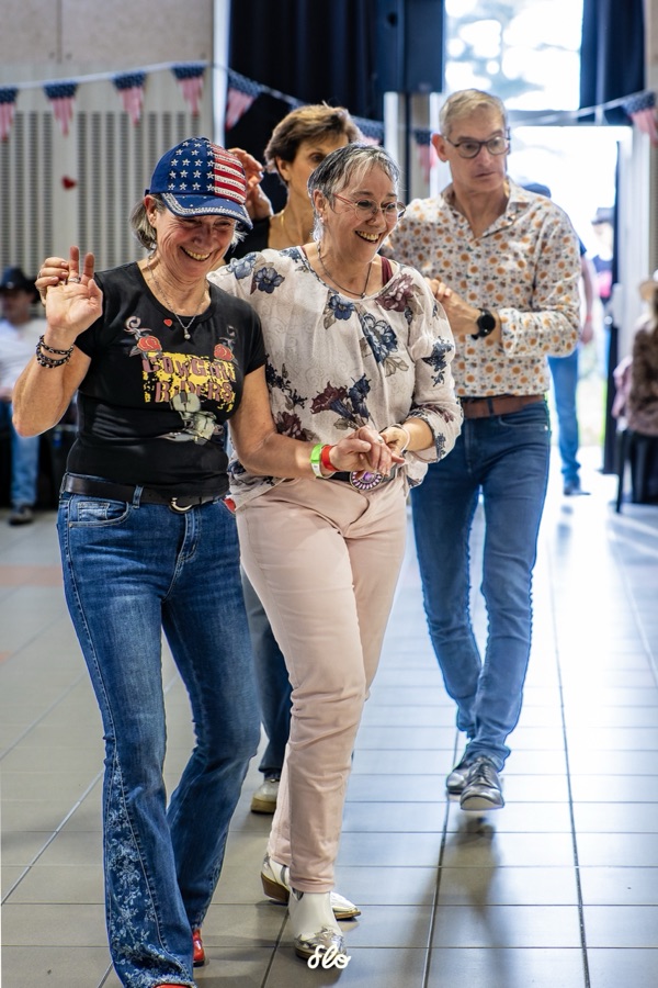 Deux danseuses riant et marchant côte à côte, casquette américaine et tenue fleurie