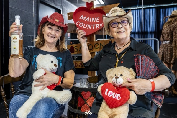 Deux participantes posant avec des peluches et un cœur Maine Country devant le décor du bal