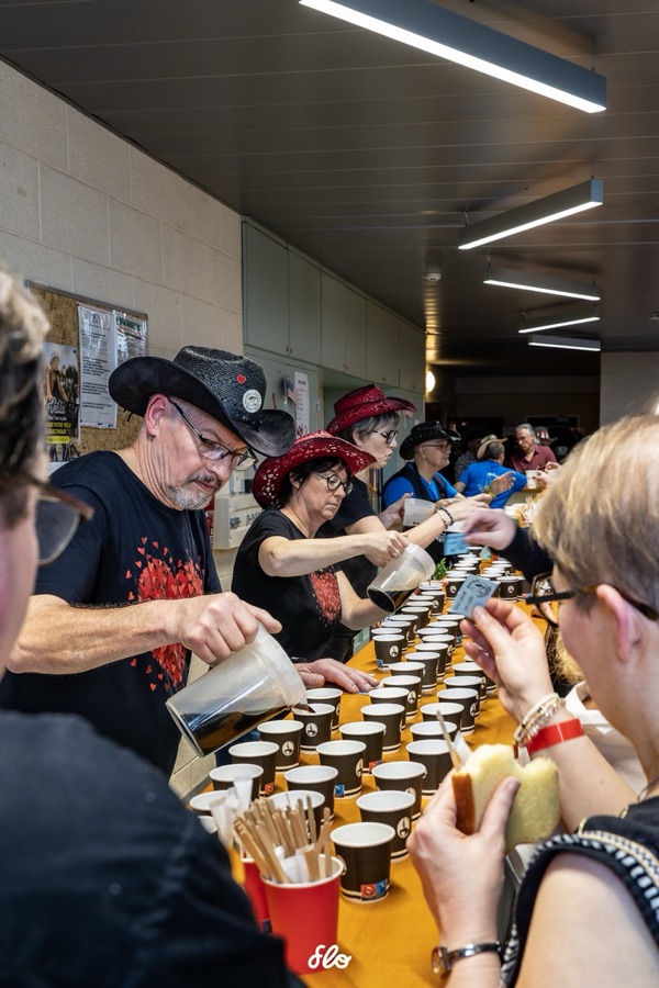 Bénévole versant du café devant une rangée de tasses alignées sur la table