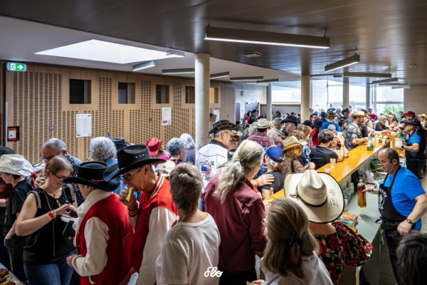 Foule de participants en chapeaux de cowboy au comptoir de la buvette pendant la pause