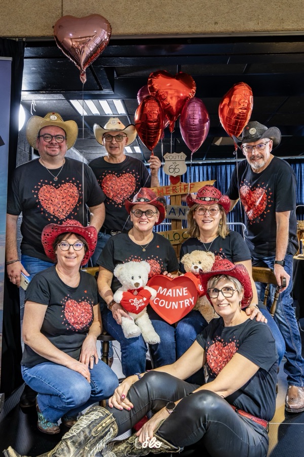Équipe organisatrice en t-shirts cœur posant devant le décor avec ballons et panneau Route 66