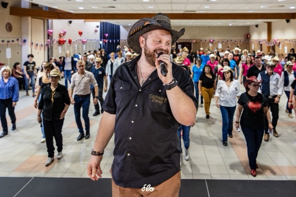 Animateur au micro chantant face aux danseurs alignés dans la salle