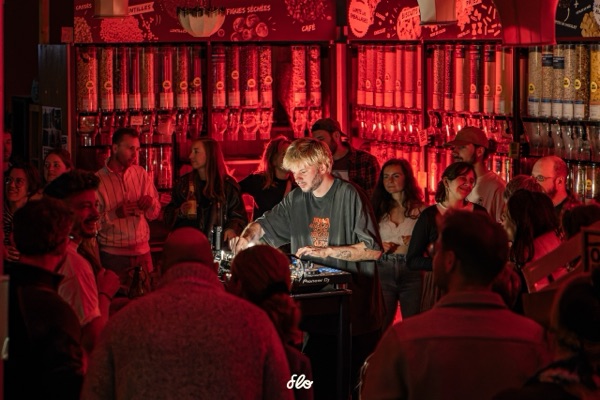 Fakear aux platines Pioneer DJ entouré du public, rayons de vrac en arrière-plan sous éclairage rouge