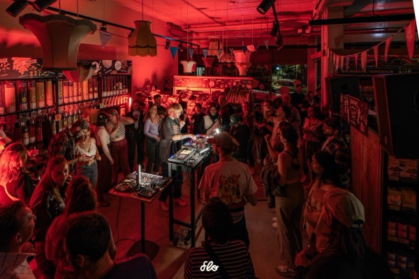 Vue d'ensemble du magasin avec le public réparti de chaque côté du DJ, affiche Fakear en fond