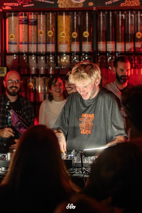 Fakear souriant derrière ses platines, échangeant avec le public au premier rang