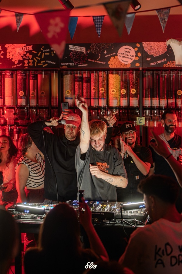 Fakear et un invité levant les bras derrière les platines, public au premier plan