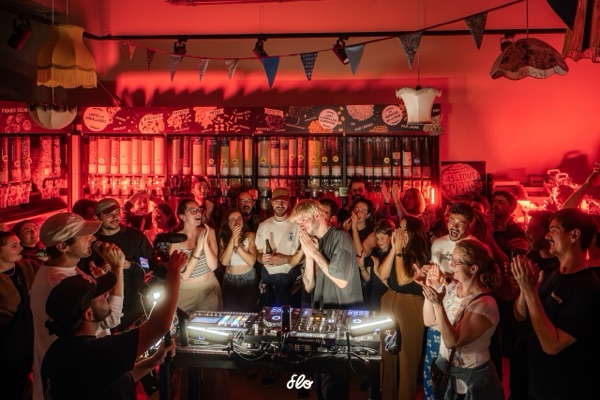 Fakear et le public applaudissant derrière les platines, visages souriants sous les guirlandes