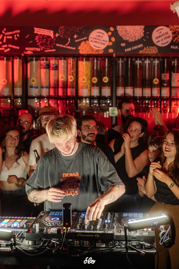 Fakear mixant, le public applaudissant et dansant face à lui sous éclairage rouge